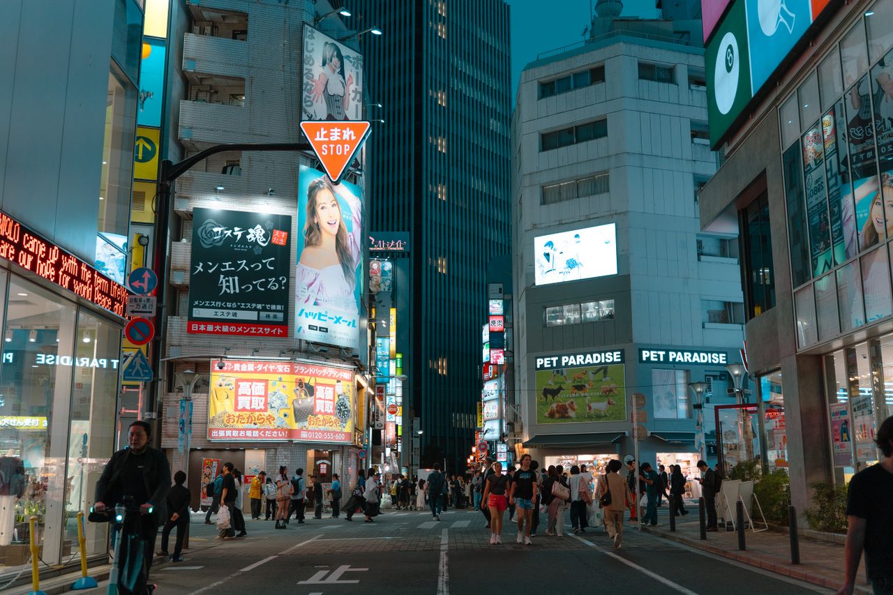 Vue nocturne captivante d'une rue animée de Tokyo, éclairée et fréquentée par la foule.